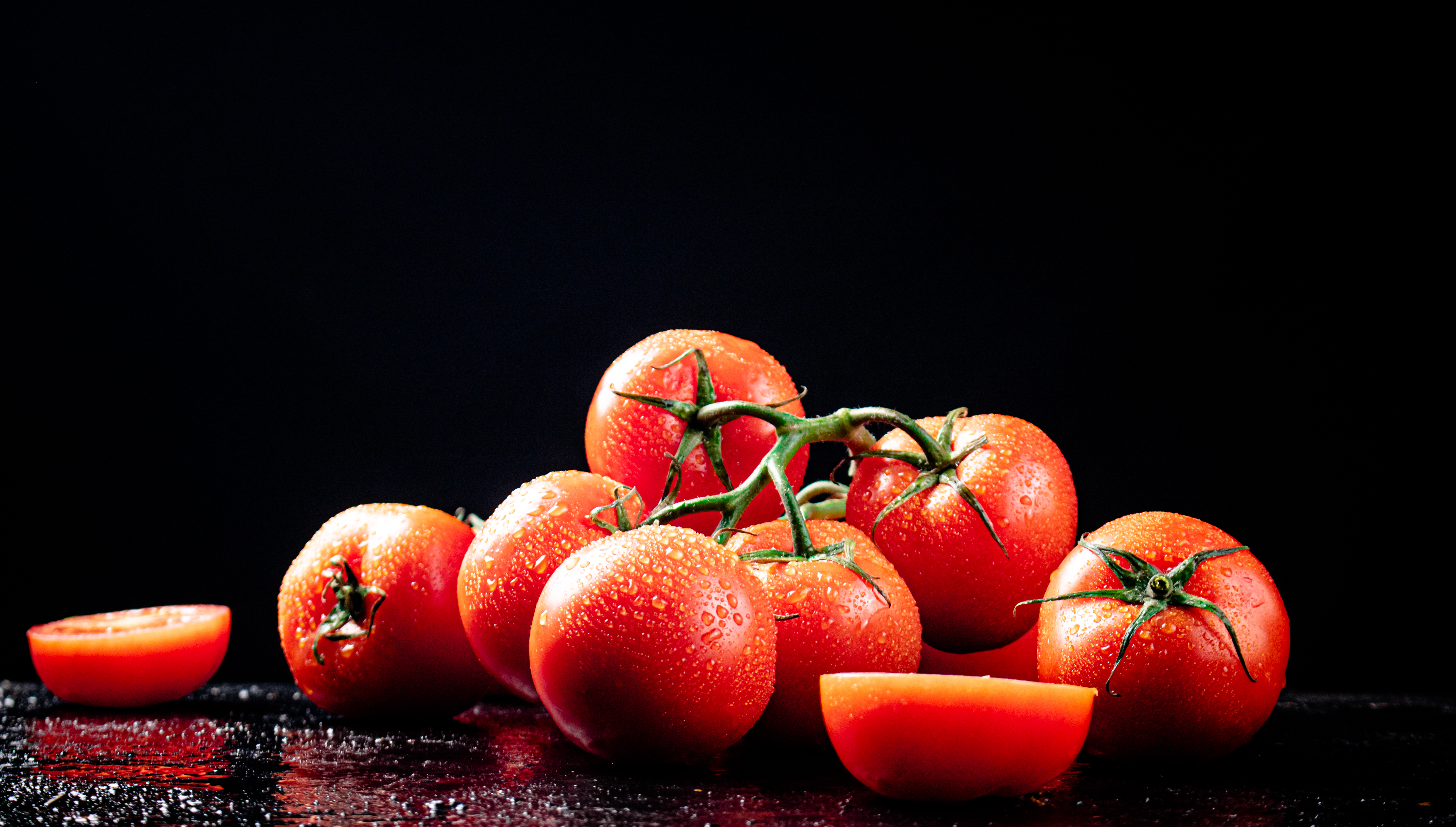 Ripe tomatoes on a branch and tomato halves.